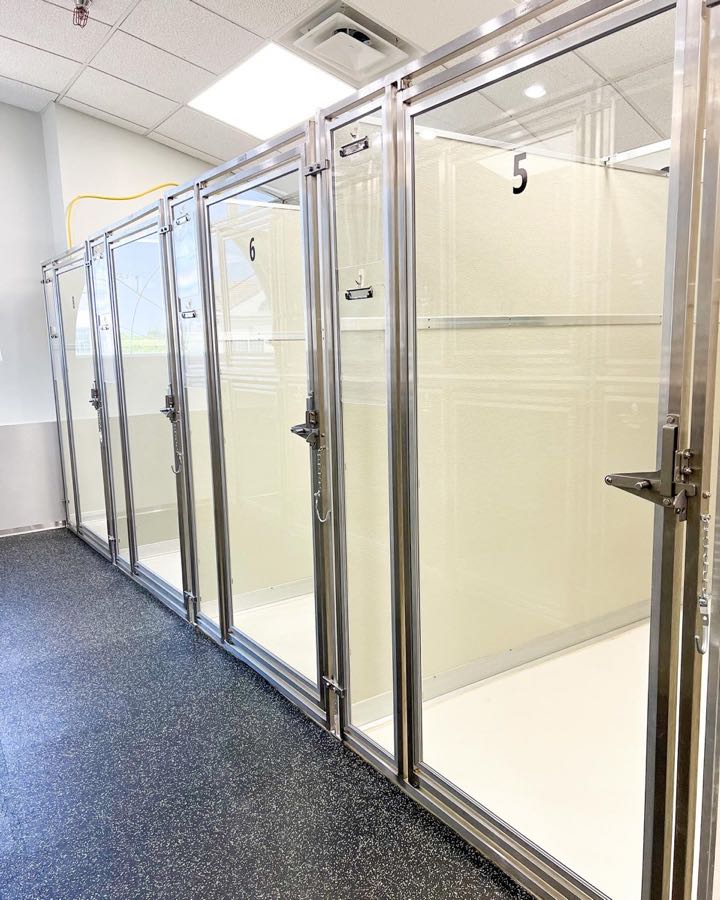 Row of empty glass-front sleeping suites at Collars Olathe, doors open, numbered 5 and 6